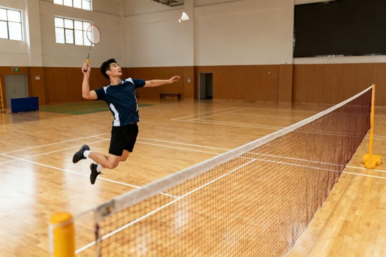 Joueur de badminton bondissant pour smasher un volant dans un gymnase lumineux