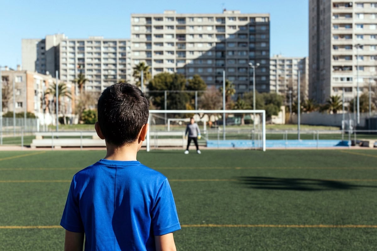 Ballon de football posé sur le rond central d'un stade urbain éclairé, tribunes vides au crépuscule