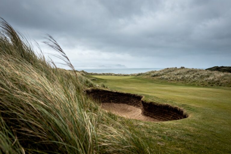 Parcours de golf en links désert dans les dunes, herbes hautes courbées par le vent