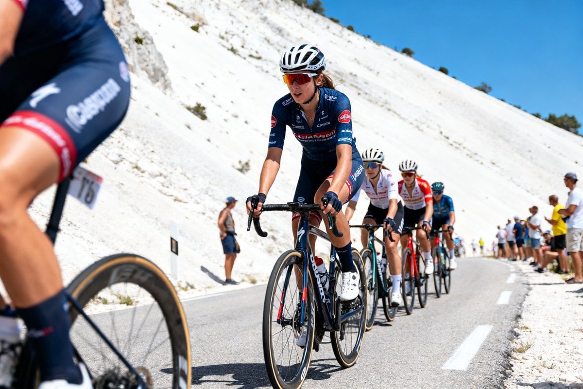 Des cyclistes féminines grimpent une route de montagne aux pentes calcaires blanches, spectateurs au bord