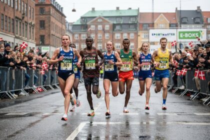 Groupe de coureurs et coureuses en maillots nationaux sur une rue mouillée de Copenhague, drapeaux danois au bord