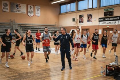 Séance d'entraînement d'un club amateur de basket, joueuses et joueurs en maillots floqués autour d'un entraîneur