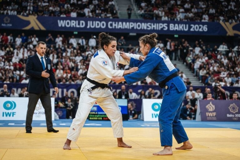 Deux judokas en judogi blanc et bleu à la saisie sur le tatami des Mondiaux de Bakou, arbitre en arrière-plan