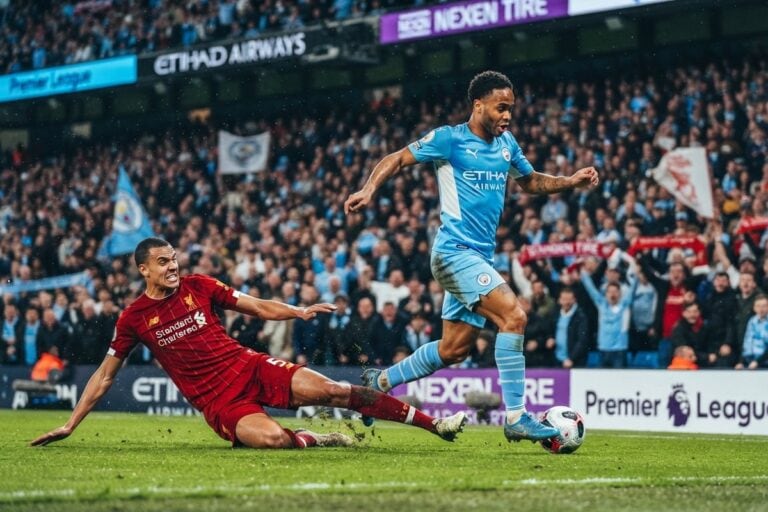 Un joueur de Manchester City en maillot bleu ciel file balle au pied devant un défenseur de Liverpool qui tacle
